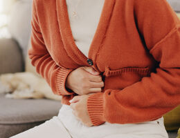 Closeup of a woman's hands wrapped around her stomach.