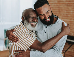 A younger man and an older man embracing.