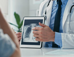 A doctor displays a tablet showing a chest scan.