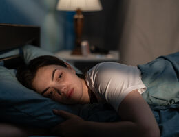 A woman lies awake in bed.