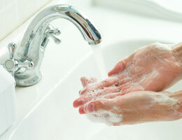 Soapy hands under a running sink tap.