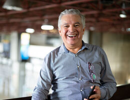 A man holding a cellphone in an indoor setting enjoys a laugh.